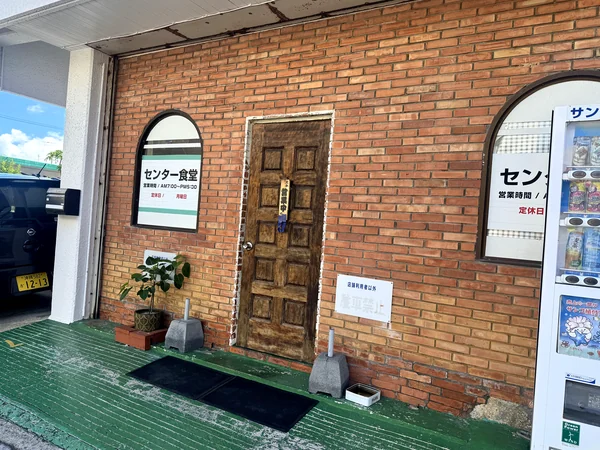 レンガ調の壁と木製の扉が特徴的な、糸満市センター食堂の入口
