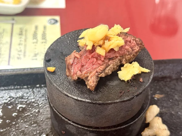 焼き石にのせた県民ステーキにオリジナルの刻みにんにくをトッピング