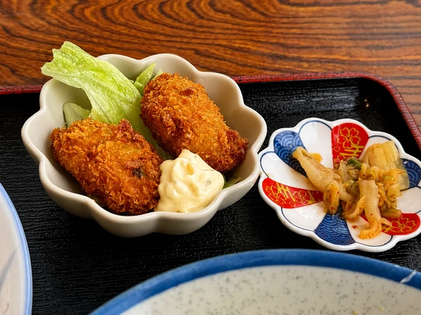 うるま市のうるまる食堂のまる得セットで選んだカキフライとキムチ。揚げたてのカキフライ2個にタルタルソースを添えた一品