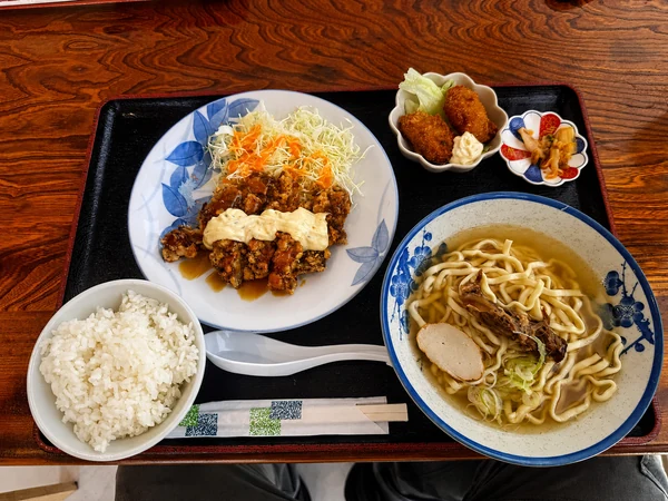 うるま市のうるまる食堂で注文した「まる得セット」。チキン南蛮、沖縄そば、ご飯、カキフライ、キムチが付いたボリューム満点のランチ