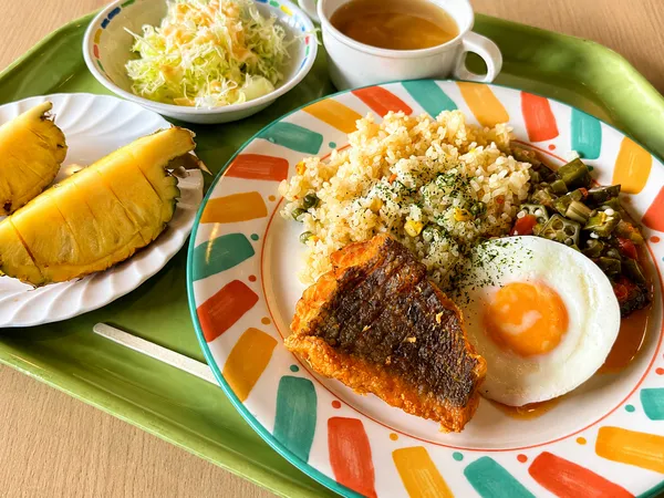 揚げ魚と目玉焼きを添えたリベリアのドライライスとサラダ、スープ、パイナップル