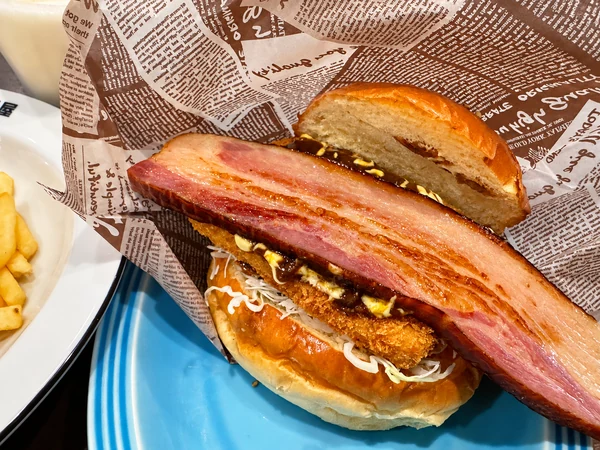 チキンカツとカレーソース、ビッグベーコンが見えるカレーバーガー