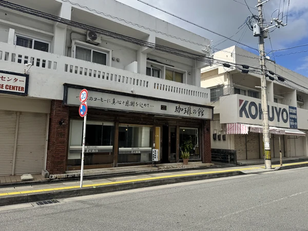 沖縄市中央にある珈琲の館の外観。大きな看板とレンガ調の壁、木製の窓枠が特徴の喫茶店